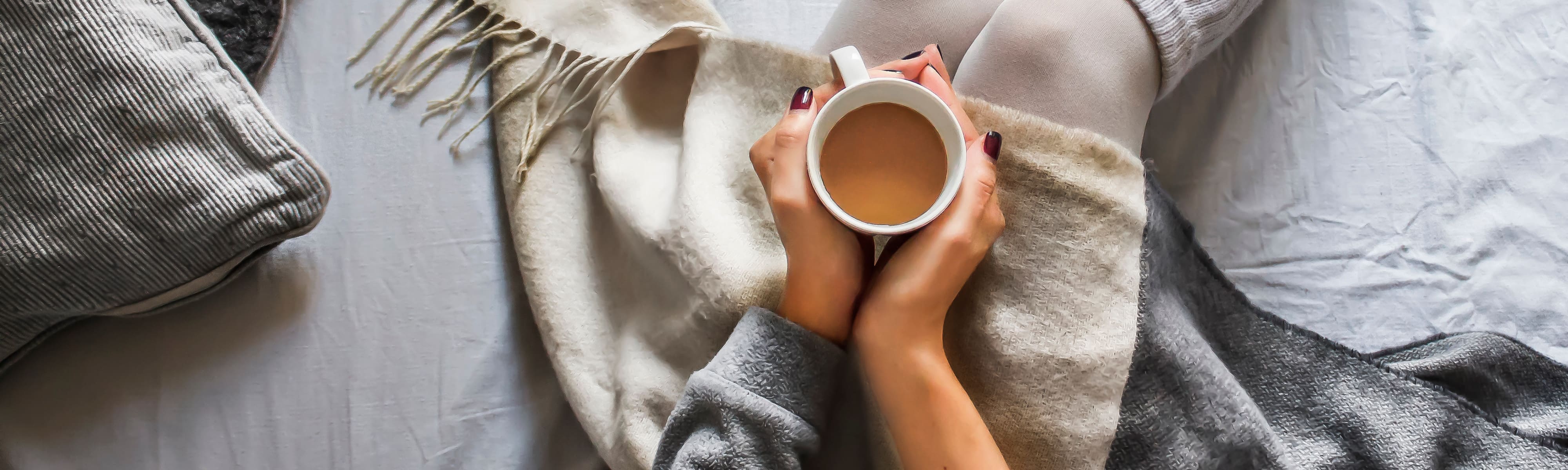 A woman sitting with a warm drink.