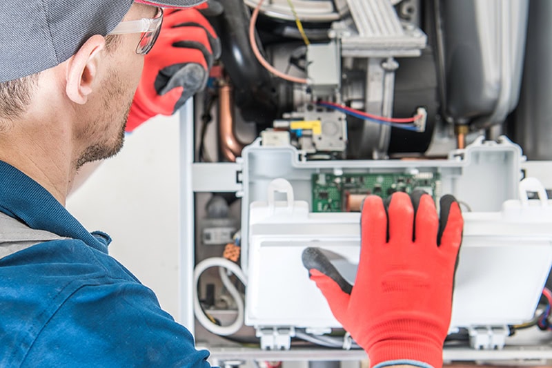 What Is That Burning Smell Coming From My Furnace? Photo of a technician performing maintenance on a furnace.